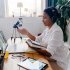 black woman infront of a laptop teaching with a book