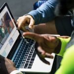 Two men looking a video on a MacBook Pro.