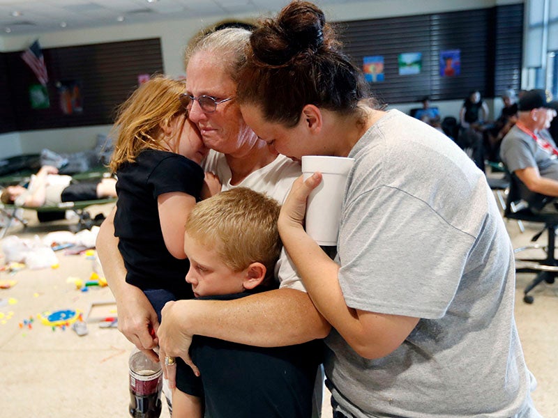 Leigh Bolding, center, cries with her daughter Kayla Cromer, right, as she holds her grandchildren at an evacuation shelter in the aftermath of Hurricane Michael. Extreme weather fueled by climate change threatens communities across the United States.