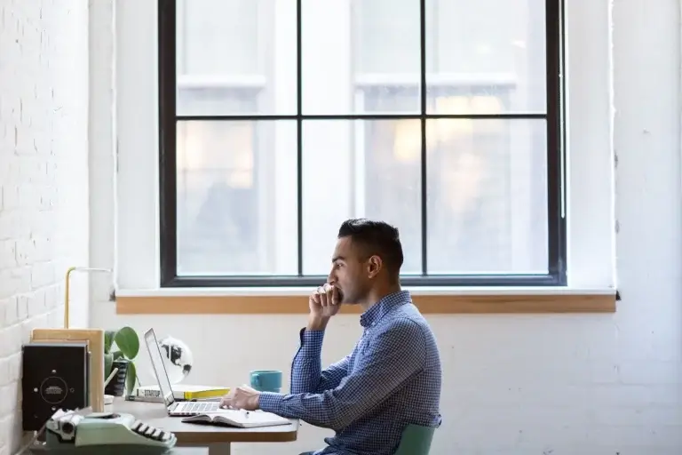 A course creator working on his laptop sitting on his desk.